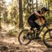 A rider navigating a dusty forest trail on a Canyon Spectral 27.5 AL 5 mountain bike.