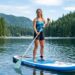 A person standing confidently with perfect balance on a wide paddle board over calm water.