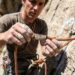 Climber inspecting dynamic rappelling rope texture and safety markings outdoors.
