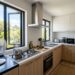 Modern small kitchen venting smoke out an open window and portable fan