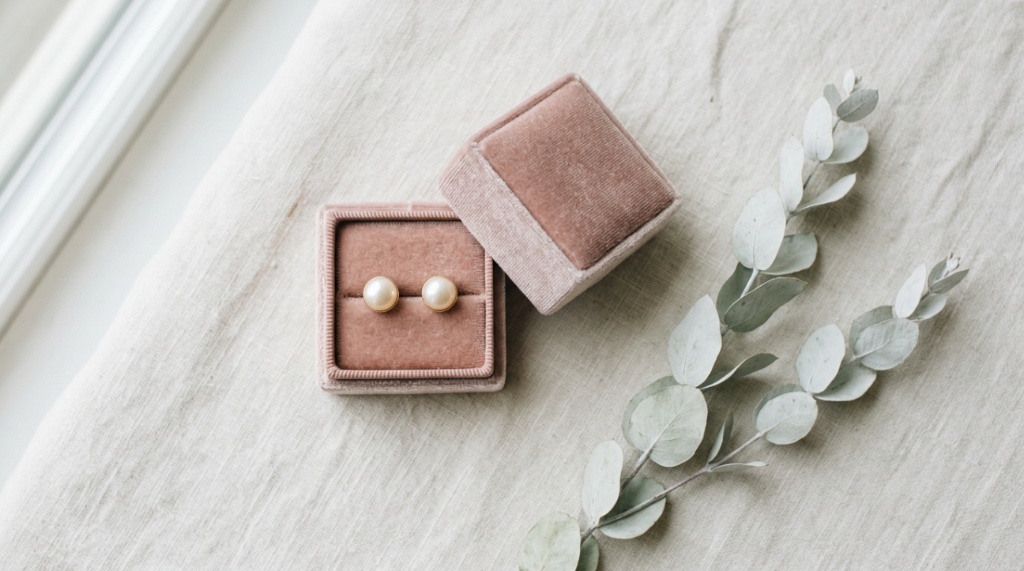 Pearl bridal earrings resting inside a velvet box with white eucalyptus.